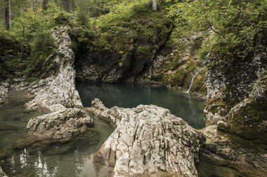 Felsen und ein ruhiger Wasserfall im Schwarzwald, umgeben von grünen Bäumen im Herbst. | © Kleinwalsertal Tourismus eGen • Fotograf: Andre Tappe
