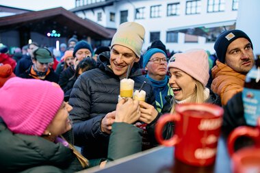 People at the snowman gathering in Kleinwalsertal, smiling and drinking warm beverages on a snowy day. | © Kleinwalsertal Tourismus eGen • Photographer: Oliver Farys